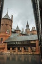 De Haar Castle with brick towers, wooden bridge and water moat on rainy day, near Utrecht.