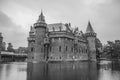 De Haar Castle facade with ornate brick towers and water moat on rainy day, near Utrecht.