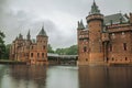 De Haar Castle facade with ornate brick towers and water moat on rainy day, near Utrecht.