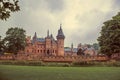 De Haar Castle with ornate brick towers, lawn wooded gardens and rainy day, near Utrecht.