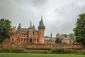 De Haar Castle with ornate brick towers, lawn wooded gardens and rainy day, near Utrecht.