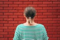 Dead end concept, rear view of casual brunette female facing the red brick wall