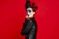 Dead gir with sugar skull makeup with a wreath of flowers on her head and skull, wearth black gloves opene her mouth in shock