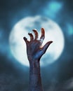 Dead hand of a zombie on the moon in the full moon background. Horror halloween concept