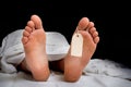 The dead man`s body with blank tag on feet under white cloth Royalty Free Stock Photo