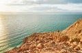 Dead sea shore at Jordan side, dry sand and rocks beach, sun shines on beautiful azure water surface Royalty Free Stock Photo