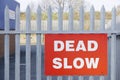 Dead slow road safety sign on industrial business park fence