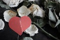 dead withered crumbling flowers roses with a red torn paper heart, as a symbol of failed love, goodbye, broken hearts, the end of Royalty Free Stock Photo