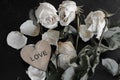 dead withered crumbling flowers roses with a wooden heart with the inscription love, as a symbol of failed love, goodbye, broken h