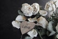 dead withered crumbling flowers roses with a wooden heart with the inscription love, as a symbol of failed love, goodbye, broken h Royalty Free Stock Photo