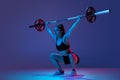 Portrait of muscled woman in sportswear training with a barbell isolated on purple background in neon light. Sport Royalty Free Stock Photo