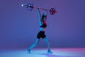 Portrait of muscled woman in sportswear training with a barbell isolated on purple background in neon light. Sport Royalty Free Stock Photo