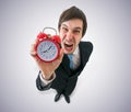 Deadline concept. Young crazy boss is screaming and holds clock in hand Royalty Free Stock Photo