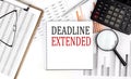 DEADLINE EXTENDED text on notebook with clipboard and calculator on a chart background