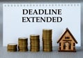 DEADLINE EXTENDED - words on white paper against the background of stacks of coins and a wooden house Royalty Free Stock Photo