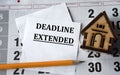 DEADLINE EXTENDED - words on white paper on the background of a house, pencil and calendar Royalty Free Stock Photo