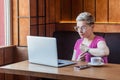 Deadline! Portrait of warning attractive young bossy girl with blonde short hair is sitting in cafe and making video call on