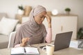 Deadline stress. Exhausted black woman in hijab tired after working on laptop for too long, having headache at home Royalty Free Stock Photo