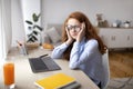 Tired girl sitting at desk with laptop