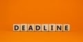 Deadline symbol. Concept word `deadline` on wooden cubes on a beautiful orange background. Business and deadline concept