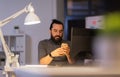 Creative man with smartphone at night office Royalty Free Stock Photo