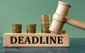 DEADLINE - word on a white sheet with a judge\'s gavel and a stack of coins in the background Royalty Free Stock Photo