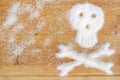 Deadly sugar addiction suggested by spilled white sugar crystals forming a skull on a wooden table Royalty Free Stock Photo