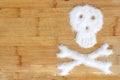 Deadly sugar addiction suggested by spilled white sugar crystals forming a skull on a wooden table Royalty Free Stock Photo