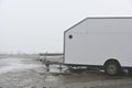 deadpan photo of a white trailer on the shore of a lake in the haze