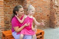 Deaf child with cochlear implant for hearing audio and aid for impairment having fun and laughs with mother outdoor in