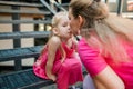 Deaf child with cochlear implant for hearing audio and aid for impairment having fun and laughs with mother outdoor in