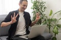 Deaf or hard hearing happy smiling young caucasian man uses sign language while video call using laptop while sitting on