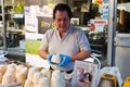 Dealer cheese Sold cheese dressed in a white shirt , hands on seller wearing blue rubber gloves. In the hands of the seller keeps