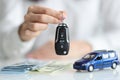 Dealer holding keys in front of toy car and money closeup Royalty Free Stock Photo