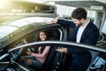 Dealer man showing a new car model to the potential customer Royalty Free Stock Photo