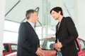 Dealer and young man with auto in car dealership Royalty Free Stock Photo