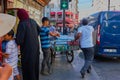 Dealers push a cart filled with water and lemonade over the footpath next to a road you`re driving on