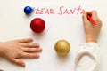 Dear Santa - wish card written by kid to Santa Claus at Christmas. Child`s hands writing letter with a red felt pen Royalty Free Stock Photo
