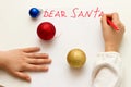 Dear Santa - wish card written by kid to Santa Claus at Christmas. Child`s hands writing letter with a red felt pen