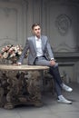 Dear young man with a haircut in a suit, sitting at a table in a room with a classic interior. Luxury. Male beauty Royalty Free Stock Photo