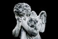 Death concept. Very ancient stone statue of little crying angel  as symbol of end of human life. Image isolated on black Royalty Free Stock Photo