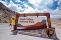DEATH VALLEY, CA: Sign for Death Valley National Park on an overcast summer day.. Woman photographer poses