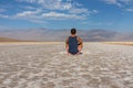 Death Valley - Rear view of man sitting on barren Badwater Basin salt flats, Death Valley National Park, California, USA