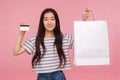Debit card for purchases. Portrait of cheerful stylish pretty asian girl holding bank card and packages Royalty Free Stock Photo