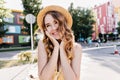 Debonair girl in straw hat playfully looking around in sunny day. Outdoor portrait of glad blonde l