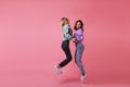 Debonair shapely girls holding hands and smiling. Studio portrait of jumping female friends expressing happiness..