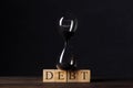 Debt, financial obligation driving economic bubble burst countdown concept, sandglass on wooden cube blocks with