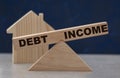 Debt and income balance on wooden scales on a dark background