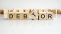 DEBTOR text on a wooden blocks, gray background