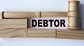 DEBTOR - word on the background of wooden blocks and a judge\'s gavel